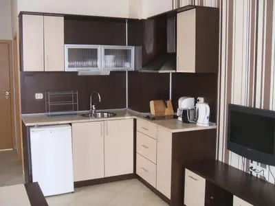 a small kitchen with white cabinets and a tv at Laguna Beach Resort & Spa in Sozopol