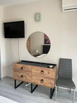 a dresser with a mirror and a chair in a room at Apartament Ivanovi A119 in Burgas City