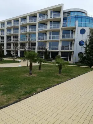 a large building with palm trees in front of it at Apartament Ivanovi A119 in Burgas City