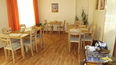a dining room with wooden tables and chairs at Hotel Palitra in Varna City
