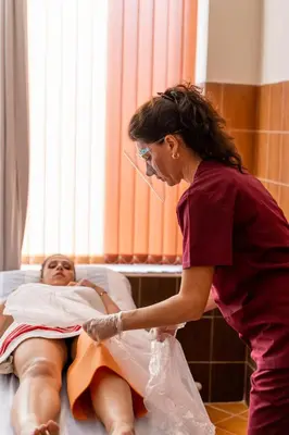 a woman laying in a hospital bed with a woman holding a blanket at Grand Hotel Pomorie - Medical spa in Pomorie
