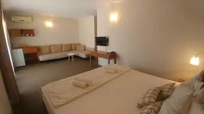 a bedroom with a large bed and a living room at Family Hotel Muses in Sozopol