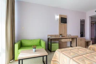 a hotel room with a green couch and a table at Ivana Palace Hotel - Free Parking in Sunny Beach
