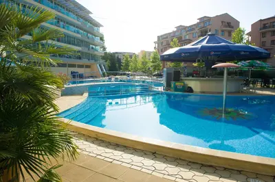 a large swimming pool with an umbrella next to a building at Ivana Palace Hotel - Free Parking in Sunny Beach