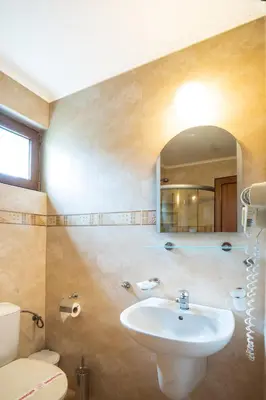 a bathroom with a sink and a toilet and a mirror at Hotel Zeus in Pomorie