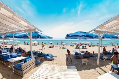a crowd of people on a beach with blue umbrellas at Grand Resort in Sveti Vlas