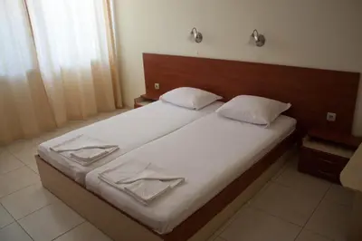 a bedroom with a large bed with white sheets at Gardenia Vacation Settlement in Sozopol