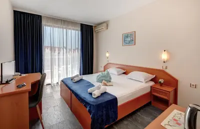 a hotel room with a bed and a desk and a computer at Семеен хотел Амон Ра in Sozopol