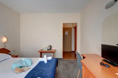 a bedroom with a bed and a desk and a tv at Семеен хотел Амон Ра in Sozopol