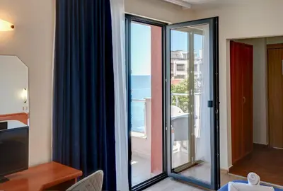 a room with sliding glass doors with a view of the ocean at Семеен хотел Амон Ра in Sozopol