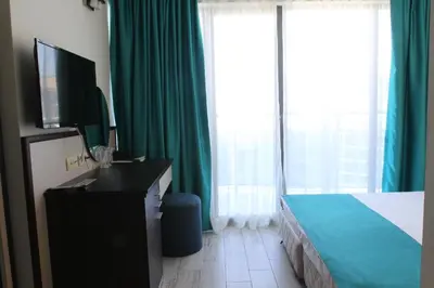 a hotel room with a bed and a television and curtains at Smartline Meridian Hotel in Sunny Beach