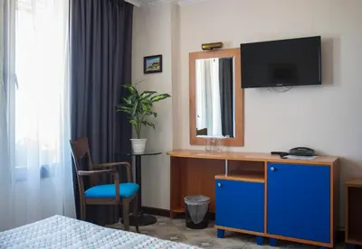 a hotel room with a desk with a tv on the wall at Victoria Hotel Nessebar in Nesebar