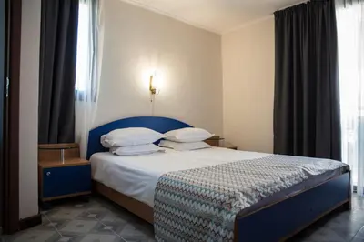 a bedroom with a bed with a blue headboard and pillows at Victoria Hotel Nessebar in Nesebar