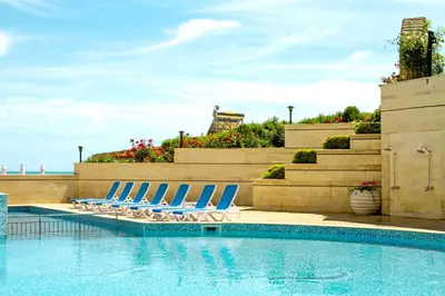 a swimming pool with lounge chairs next to a swimming pool at Bilyana Beach Hotel- Adults only in Nesebar