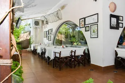 a restaurant with tables and chairs and an archway at Marina Cape Vacation Complex in Ravda