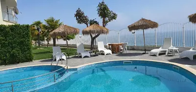 a swimming pool with chairs and a table and umbrella at Alex Beach Apartment in Sveti Vlas