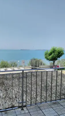 a fence next to a beach with a tree at Alex Beach Apartment in Sveti Vlas
