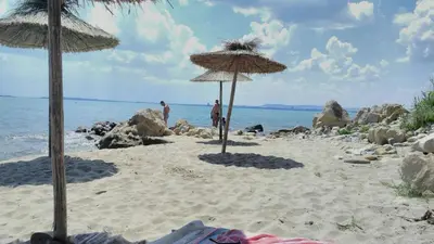 two straw umbrellas on a sandy beach with the ocean at Alex Beach Apartment in Sveti Vlas