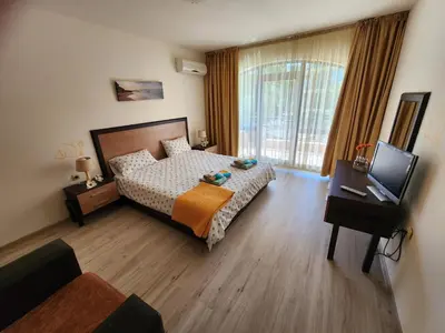 a bedroom with a bed and a desk and a television at Villa Bonita Apartment in Sunny Beach