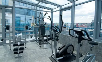 a gym with cardio equipment in a building with windows at Regata Palace Hotel in Sunny Beach
