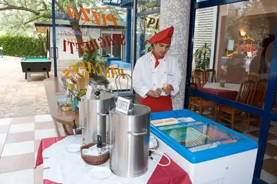 a chef standing in front of a food stand at Dunav Hotel in Sunny Beach