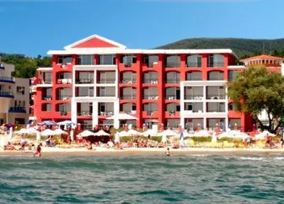 a red and white building on a beach next to the water at Carina Beach in Sunny Beach