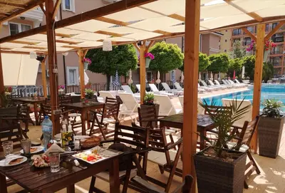 a restaurant with tables and chairs and a swimming pool at Tropics Hotel - Ultra All Inclusive in Sveti Vlas