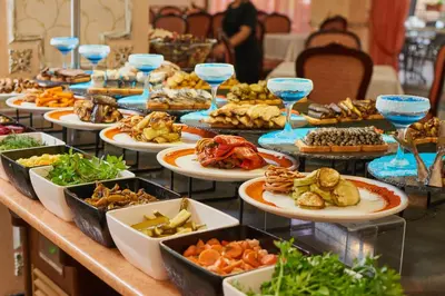 a buffet line with plates of food and wine glasses at Karolina Hotel in Sunny Beach
