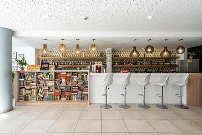 a restaurant with a bar with white stools in a room at iHotel Sunny Beach in Sunny Beach