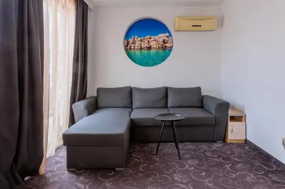 a living room with a couch and a mirror at Семеен Хотел Опера in Burgas City