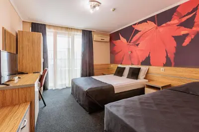 a hotel room with two beds and a television at Семеен Хотел Опера in Burgas City