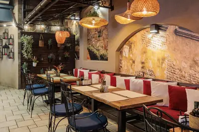 a restaurant with wooden tables and chairs in a room at Семеен Хотел Опера in Burgas City