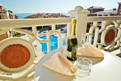 a table with a bottle of wine and glasses on a balcony at Saint George Palace Hotel All-inclusive in Sveti Vlas