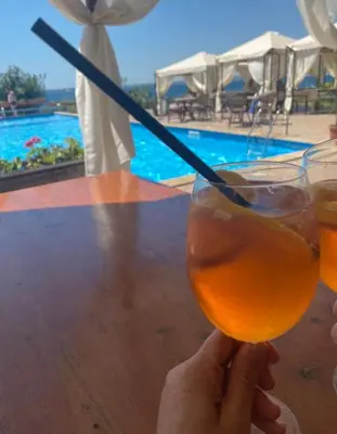 a person holding a drink at a table next to a pool at Dolce Vita Apartment in Sveti Vlas