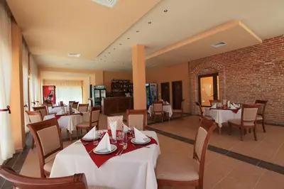 a restaurant with white tables and chairs and a brick wall at Galeria Holiday Apartments in Obzor