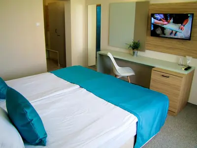 a hotel room with a bed and a desk and a television at Hotel Lotos in Kiten