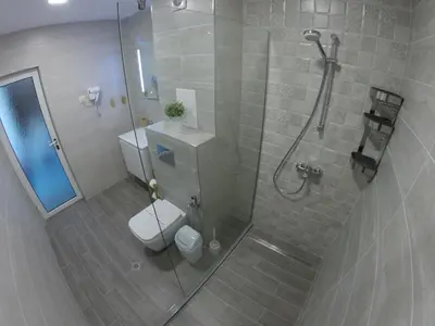 a bathroom with a shower with a toilet and a glass shower stall at Hotel Lotos in Kiten