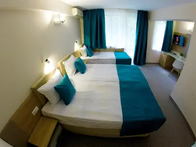a hotel room with two beds with blue pillows at Hotel Lotos in Kiten