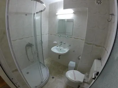 a bathroom with a shower and a toilet and a sink at Hotel Lotos in Kiten