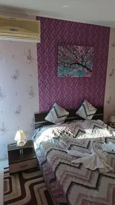 a bedroom with a bed with a purple wall at Apartment Sianie в центъра на Слънчев бряг, само на няколко крачки от плажа in Sunny Beach