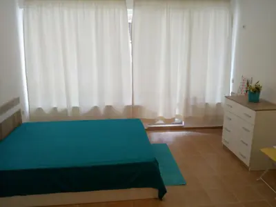 a bedroom with a bed and a dresser and curtains at Studio Zlatina in Pomorie