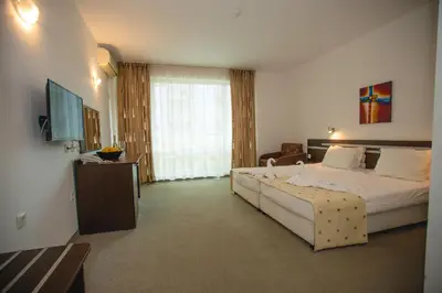 a hotel room with a large bed and a television at Deva Hotel - All Inclusive in Sunny Beach
