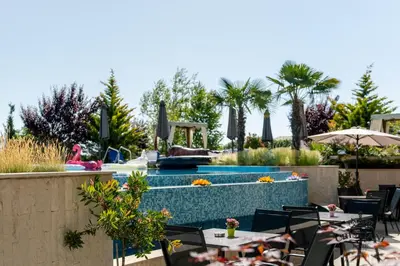 a pool at a resort with tables and chairs at Cristiani Hotel Sozopol in Sozopol