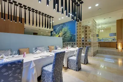 a dining room with a long table and blue chairs at Royal Beach Apartments in Sunny Beach