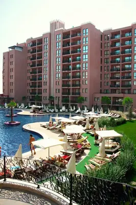a pool with chairs and umbrellas in front of buildings at Royal Beach Apartments in Sunny Beach