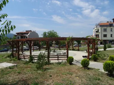a wooden pergola in a park with a fountain at Blue House in Tsarevo