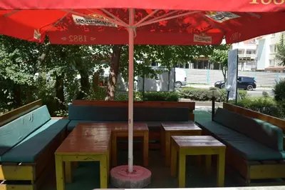 a table and benches with a red umbrella at Hotel Klisura in Sunny Beach