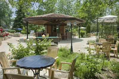 a table and chairs in a garden with a gazebo at Regina Hotel in Sunny Beach