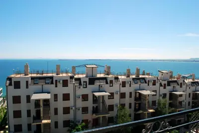 an apartment building with the ocean in the background at Hotel Saint Tatyana in Sveti Vlas