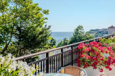 a balcony with a table and chairs and flowers at Apolon Complex in Sozopol